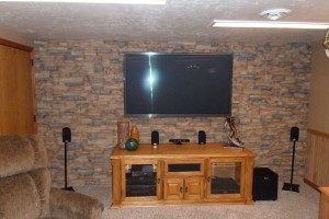 Basement converted into a man cave, complete with a stacked stone accent wall.