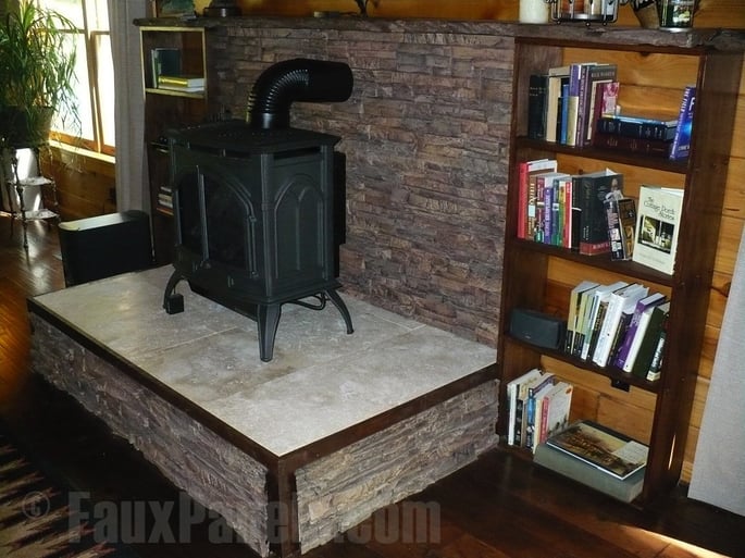 Rustic wood stove area with a raised platform and stone panels