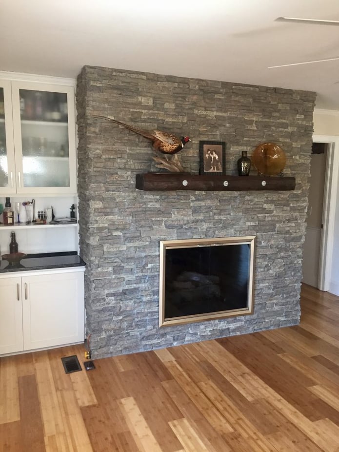 An outdated brick fireplace covered in stacked stone style panels made it look brand new.