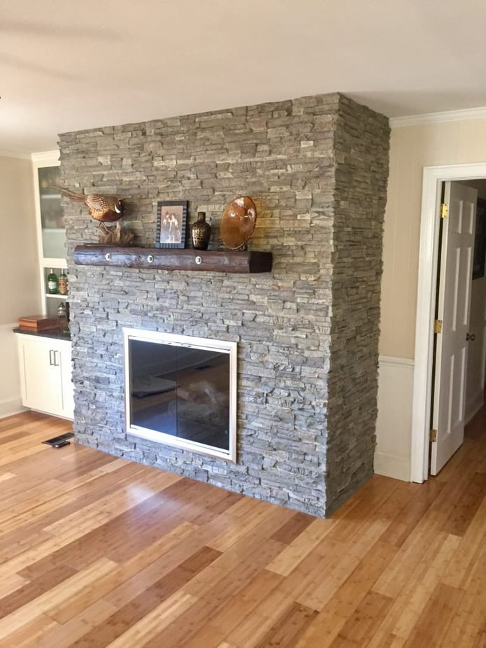 Brick living room fireplace covered in panels that look like real stone.
