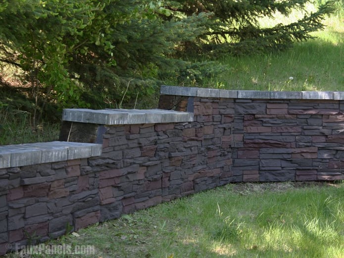 A graduating retaining wall outfitted with artificial stacked stone paneling.